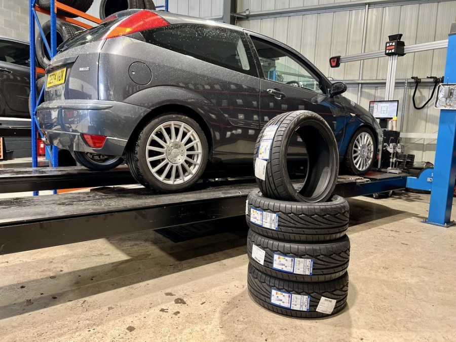 stack of tyres placed in front of grey Ford Focus ST170