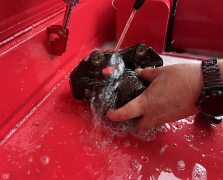Brake caliper being cleaned in a parts washer